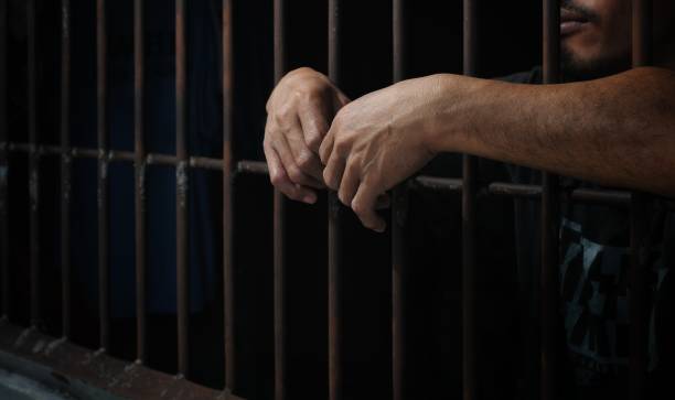 istock hands of a prisoner behind prison bars 2149178122