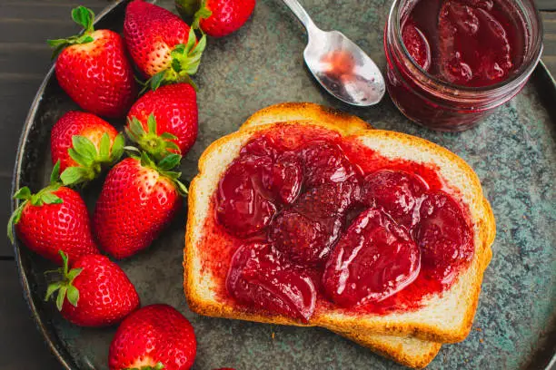 Sliced and toasted white bread and homemade strawberry preserves with large pieces of fruit