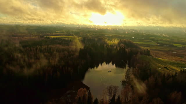 Dramatic aerial landscape view towards sun on golden hour with moving clouds