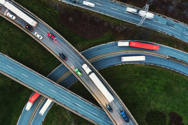 Truck Traffic on Highway Interchange Aerial view of trucking traffic on a November evening. Composite image. drone point of view road stock pictures, royalty-free photos & images