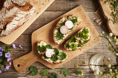 Three slices of bread with spring wild edible plants - onion grass, garlic mustard and ground elder
