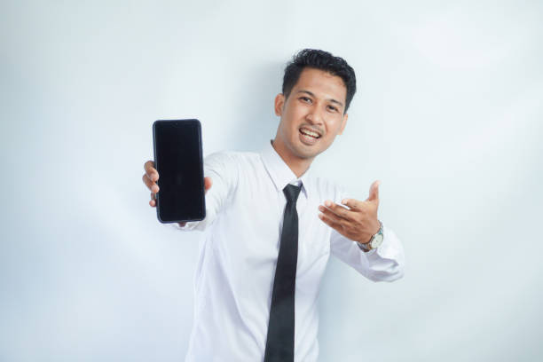 istock Adult Asian man standing while smiling showing blank mobile phone screen that he hold 2149181038