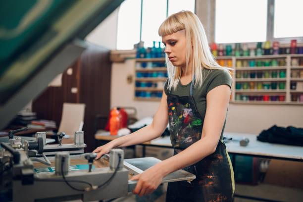 istock Print shop worker putting screen printing plate on machine at facility 2149181342