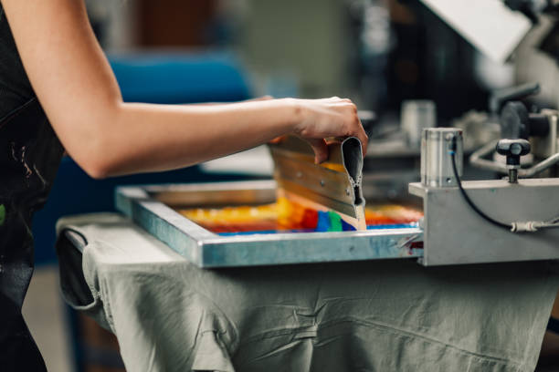 istock Close up of graphic worker's hands with squeegee silkscreen printing. 2149181344