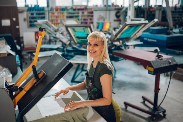 istock Portrait of print shop worker using heating press on textile product. 2149181352