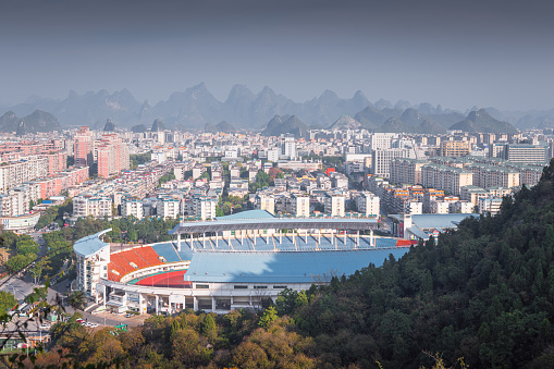 Stadium and the city buildings surrounded by the limestone mountains, Guilin, China