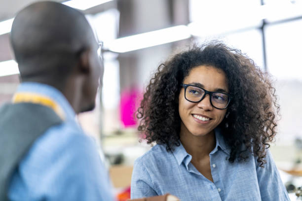istock African - american young colleagues having discussion at a clothes manufacturing studio, the woman sewing at a modern sewing machine 2149181808