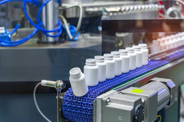 istock Moving polypropylene white bottles on conveyor belt of automatic liquid filling machine 2149182258