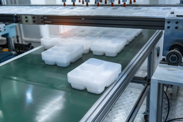 Stack of polypropylene food containers on conveyor belt of automatic plastic injection molding machine,automated technology concept
