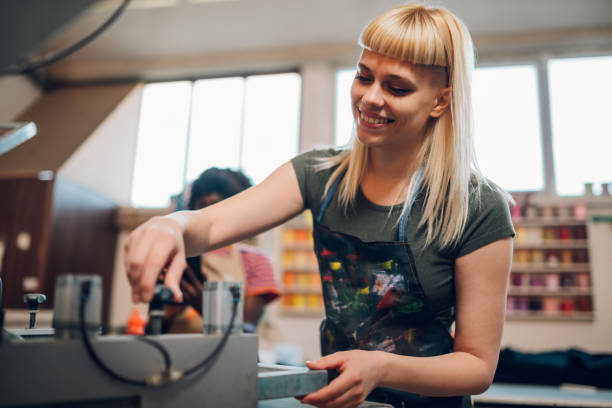istock Smiling graphic worker operating screen printing press at print shop. 2149182746