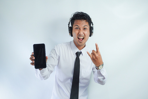 Adult Asian man smiling confident while pointing finger to blank handphone screen