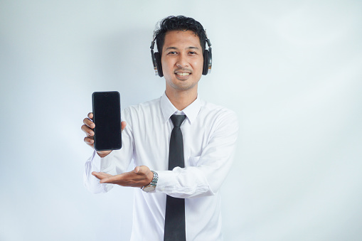 Adult Asian man smiling confident while pointing finger to blank handphone screen