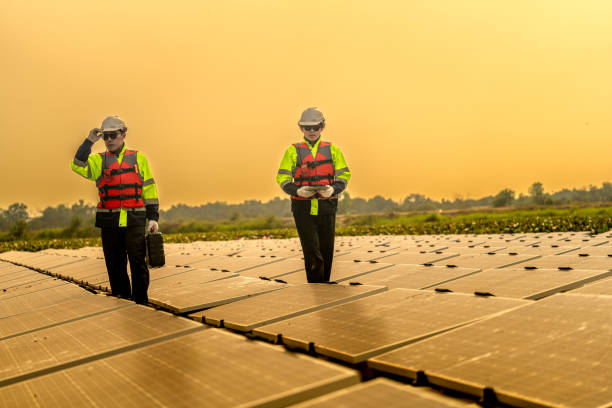 istock Male workers repair Floating solar panels on water lake. Engineers construct on site Floating solar panels at sun light. clean energy for future living. Industrial Renewable energy of green power. 2149184967