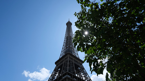 Eiffel Tower close up, famous Paris French capital monument of steel in the city centre, tourist attraction and the most visited landmark against the blue sky in sunlight, sun beams
