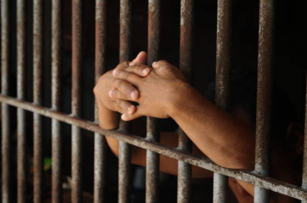 istock hands of a prisoner behind prison bars 2149185486