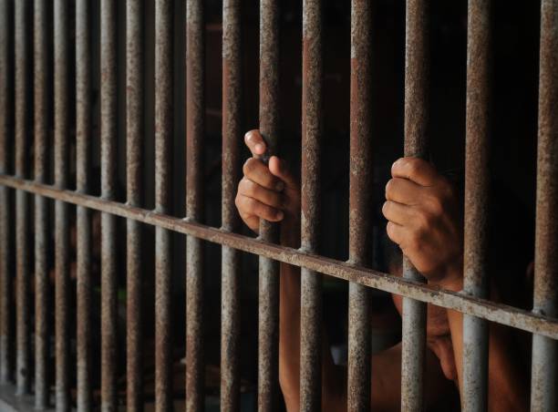 istock hands of a prisoner behind prison bars 2149185745