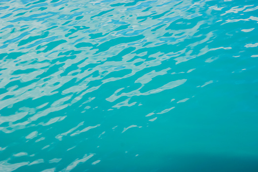 Clear turquoise water surface texture with ripples on the surface