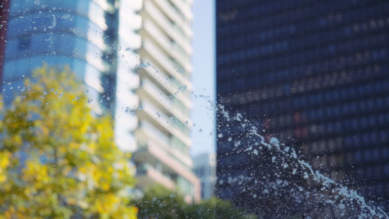 Water fountain splashes against the buildings and autumn trees