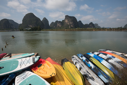 Yangshuo County, Guilin City, Guangxi, China - October 28, 2023: Paddle boards and canoes on the waterfront for tourists to enjoy water recreation
