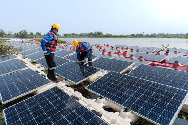 istock Male workers repair Floating solar panels on water lake. Engineers construct on site Floating solar panels at sun light. clean energy for future living. Industrial Renewable energy of green power. 2149187444