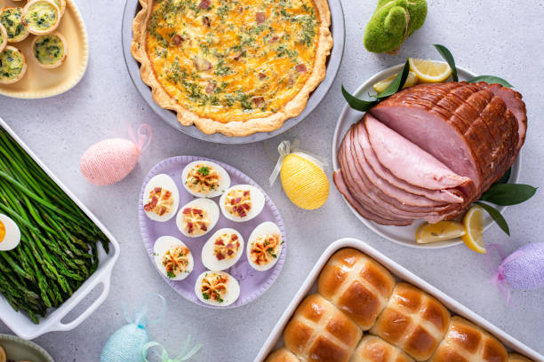 istock Easter brunch on large table with spiral sliced ham, quiche, deviled eggs and hot cross buns 2149187720