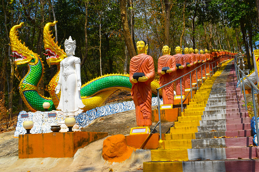 wat phra that doi ku kaew mekwanaram, way up the mountain, Pa Maet, Mueang Phrae District, Thailand, stairs on the mountain, long row of monk statues with donation pots, white sculpture of a goddess, double snake sculptures, forest, artwork, crafts, attraction, point of interest