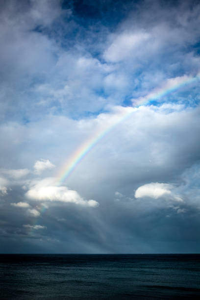 istock Seascape of a rainbow piercing clouds above the ocean 2149191504