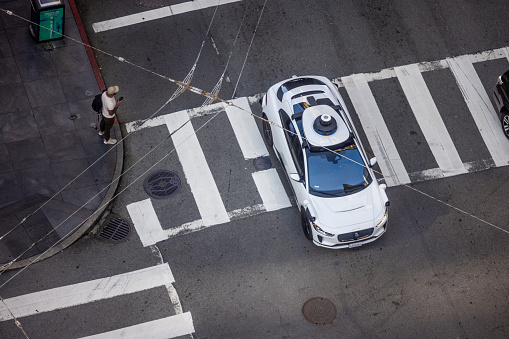 San Francisco, CA, USA - April 18, 2024: High angle view of an Alphabet's Waymo self-driving car in downtown San Francisco on Bush and Sansome Streets as it drives and transports passengers.