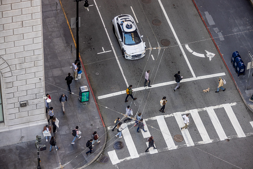 San Francisco, CA, USA - April 18, 2024: High angle view of an Alphabet's Waymo self-driving car in downtown San Francisco on Bush and Sansome Streets as it drives and transports passengers.