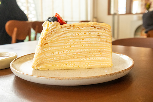 Crepe cake decorated with blueberries and strawberries on top.
