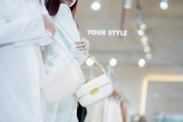 Detail shot of a stylish handbag on a woman's shoulder as she shops for clothes in a boutique.