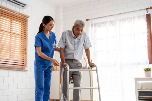 istock Asian senior elderly man patient doing physical therapy with caregiver. Attractive specialist carer women help and support older mature male practice walking slowly with walker at nursing home care. 2149194190