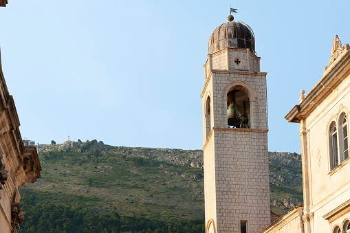 Belltower with hill background under blue sky in Dubrovnik, Croatia.