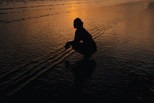 Silhouette of woman on calm beach and sky In the evening at Ao Nang, Krabi, go to the beach.