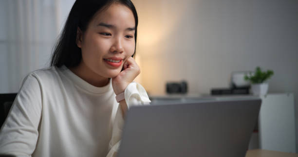 istock Smiling young woman using laptop at home. 2149197481