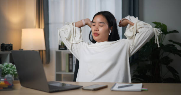 istock Young woman stretching arms while sitting at desk in home office. 2149197564