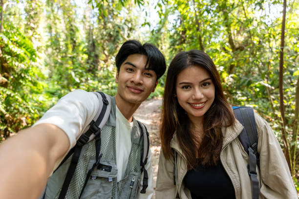istock Asian two young backpacker vlogger have fun travel in forest together. Attractive man and woman friend traveler use camera record video vlog and walking in nature wood with happiness during holiday. 2149197902