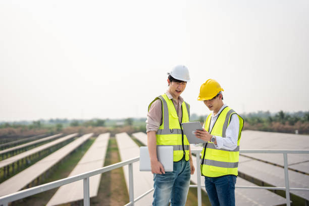 istock Professional engineer work to maintenance of photovoltaic panel system. Attractive technician worker working on roof inspect and check solar cell panels equipment box at solar cell field during sunset 2149198915