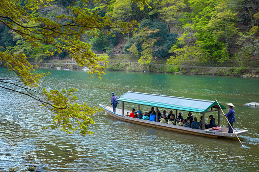 Kyoto, Japan - April 5 2023: Unidentified people ride a boat that sails in Katsura river  in Arashiyama district