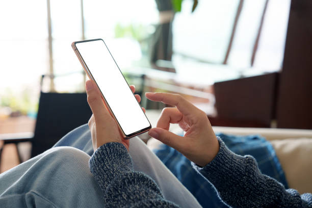 istock In the cropped image, an Asian woman is sitting relaxed on the sofa, using a blank screen smartphone. 2149201162