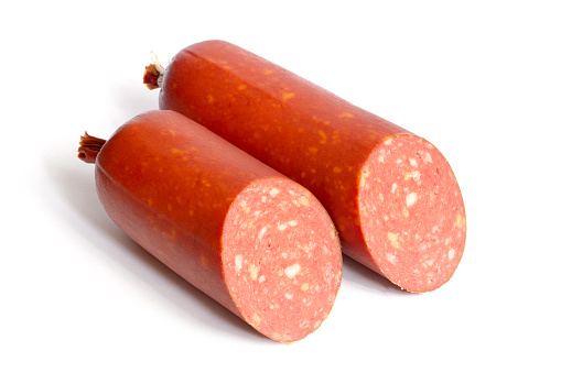 Two halves of smoked salami sausage with cheese on a white background. Fresh chopped sausage close-up.