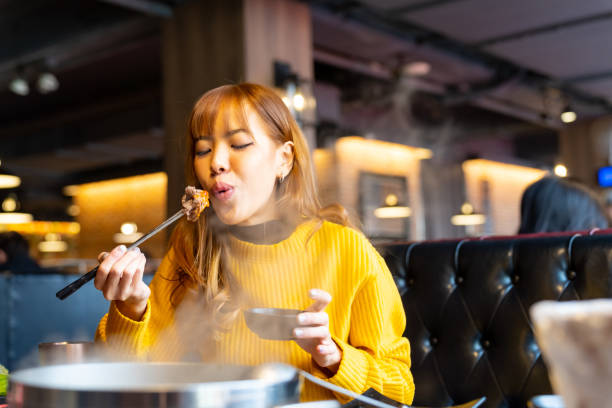 Asian woman having lunch eating hot pot at restaurant