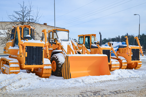 Construction machinery in warehouse during winter and snow cover. Crawler dozers without assembled work equipment. Heavy industry. Construction equipment.