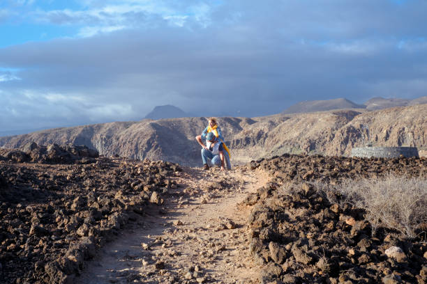 istock Active couple enjoy hiking outdoors leisure activity together in volcanic scenery destination. Travel people lifestyle. Adventure and hike active lifestyle outside. Mountain and sky backgorund 2149206832