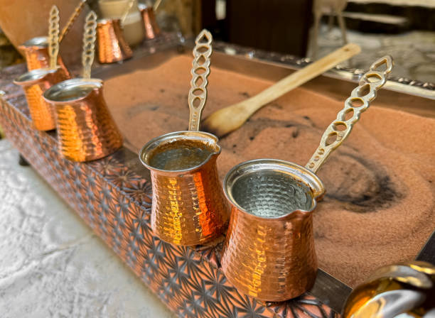 istock Traditional Turkish coffee in copper turks with long handles on tray with sand. Real coffee preparation, close up with selective focus. 2149207121
