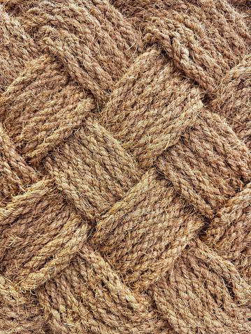 Close up of interwoven natural jute ropes creating textured pattern for rustic backgrounds and sustainable material concept. High quality photo