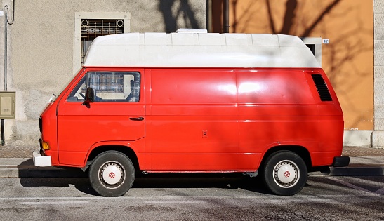 Udine, Italy. March 24, 2024. Vintage red Volkswagen Transporter T3, or Vanagon, panel van and camper produced from late Seventies. Side view.