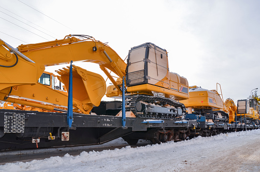 Excavators crawler transported by rail. Crawler dozers secured for rail transport. A train with wagons on a railway siding with excavators crawler.