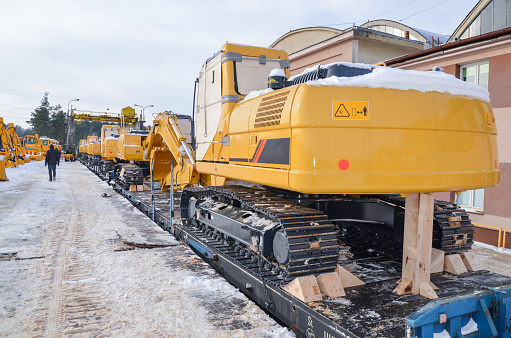 Excavators crawler transported by rail. Crawler dozers secured for rail transport. A train with wagons on a railway siding with excavators crawler.
