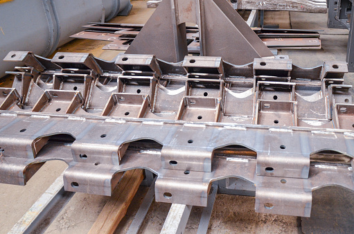 Preparation of welded parts for assembly of crawler dozers and wheel loaders. Storage station spare parts before painting components. Crawler bulldozer assembly line. Heavy industry. Construction equipment.